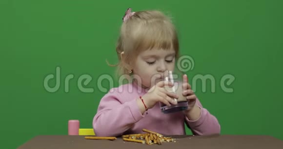 孩子吃饼干一个小女孩坐在桌子上吃饼干视频的预览图