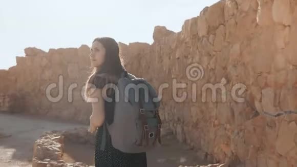 可爱的女孩带着背包走在古老的废墟上漂亮的欧洲女游客探索以色列马萨达堡垒4K视频的预览图