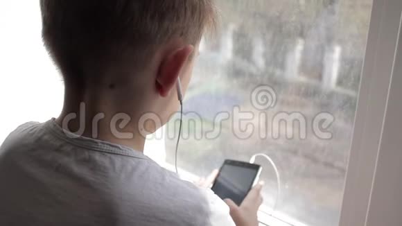 小男孩在家里用耳机听音乐视频的预览图
