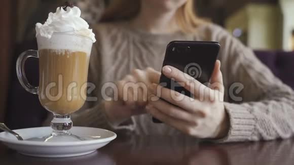 在咖啡馆里拿着智能手机的年轻女孩喝咖啡上网看新闻视频的预览图