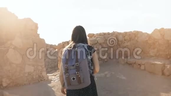 带背包的女孩探索古老的沙漠废墟在以色列马萨达漂亮的女人走在山上的堡垒墙上4K视频的预览图