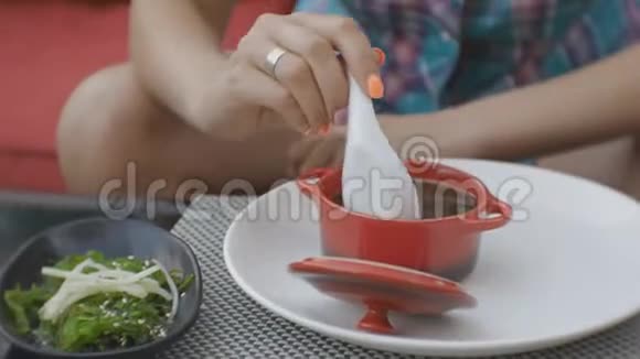 有魅力的年轻白种人女人在日本餐馆的露天平台上品尝泥锅上的汤视频的预览图