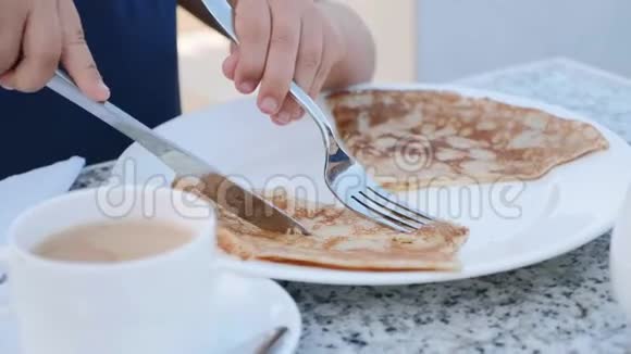小女孩正在用刀叉切煎饼作为早餐视频的预览图