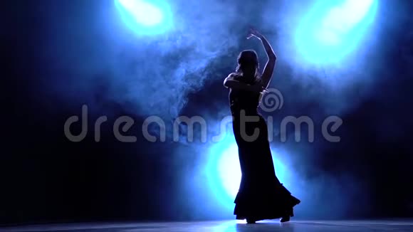 弗拉门戈黑暗房间里的舞者用她的手表演优雅的动作从后面发光烟雾背景视频的预览图