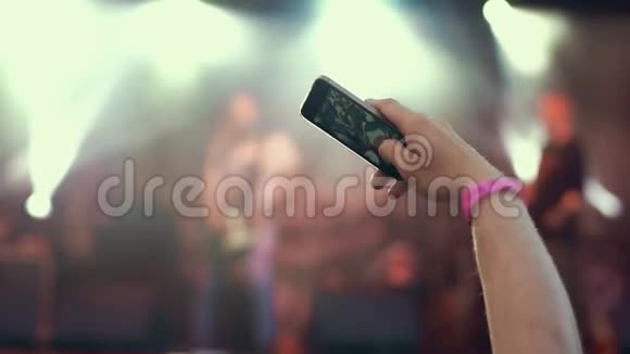 露天摇滚音乐会的人群聚会站在人群中的年轻女子手持智能手机拍摄视频视频的预览图
