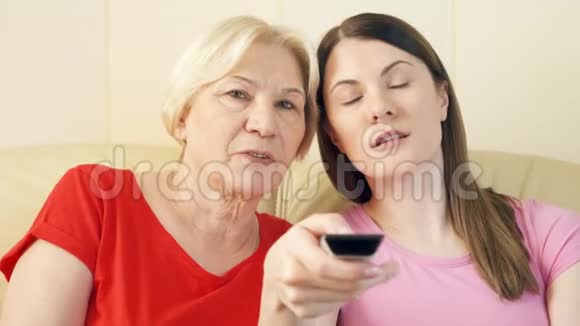 母女俩在家里沙发上放松看电视遥控开关通道视频的预览图