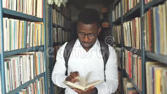 年轻的阿拉伯胡子男学生在图书馆书架间挑选书视频的预览图
