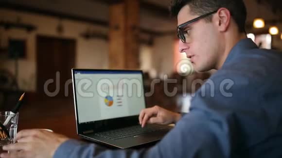 后视自由职业者商人工作在笔记本电脑与图表屏幕上的咖啡馆然后喝一杯咖啡男子视频的预览图