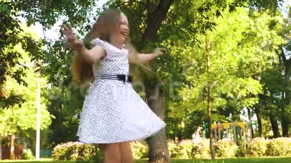 十几岁的女孩穿着白色圆点连衣裙在一个夏天的公园里微笑视频的预览图