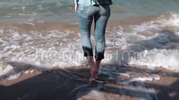 漂亮的欧洲女孩在海边试水美丽的女人对着镜头微笑风吹在头发上慢动作视频的预览图