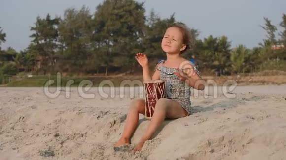 可爱的小女孩在沙滩上打鼓视频的预览图