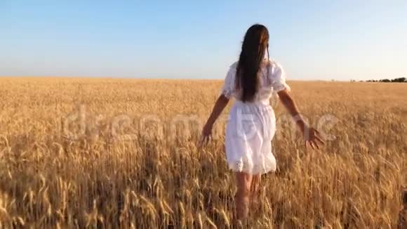 快乐的女孩穿着白色的裙子在成熟的小麦上跳舞慢动作视频的预览图