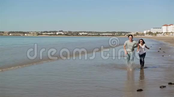 情侣手牵手背景海滩海洋日出人们拥抱和看待后景海景一对情侣视频的预览图