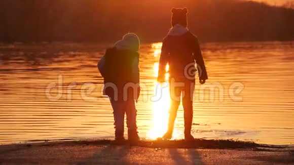 孩子们在日落时在湖上玩耍一个小女孩和男孩的剪影下次在一起跑步和玩耍这就是视频的预览图