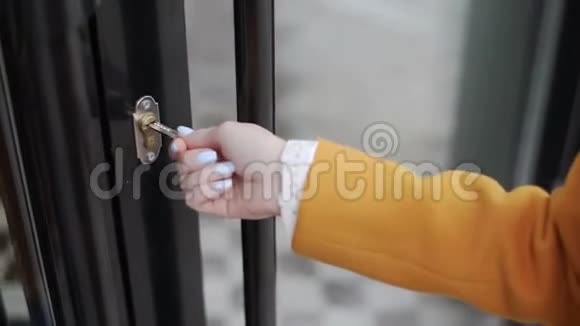 穿黄色外套的女人用钥匙打开咖啡馆的门视频的预览图
