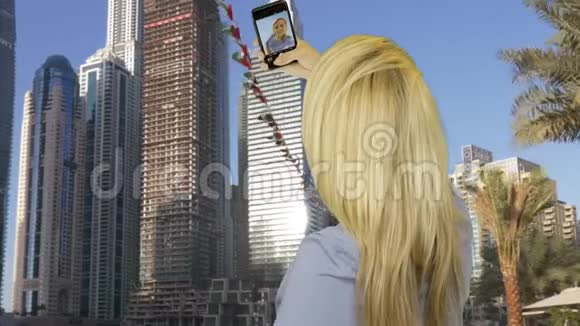 幸福的女人在商场摩天大楼对面的智能手机上自拍视频的预览图