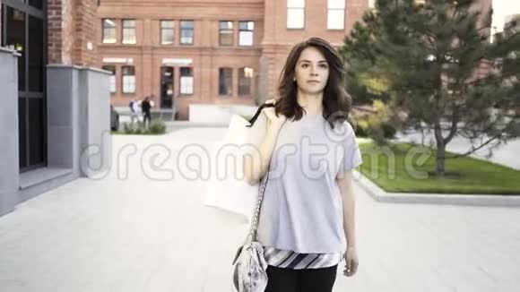 一个严肃的黑发女人在阳光明媚的夏日街头从商店里走出来视频的预览图