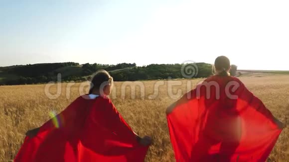 女孩们扮演超级英雄在阳光的照耀下带着小麦跑过田野慢动作视频的预览图