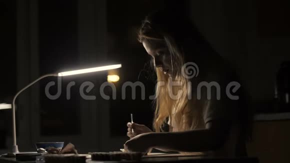 肖像女艺术家在黑暗的房间里用画笔在相册里画画视频的预览图