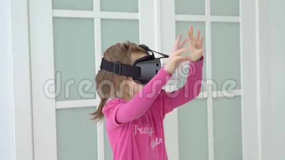 小女孩正在玻璃门背景的房间里玩虚拟眼镜视频的预览图