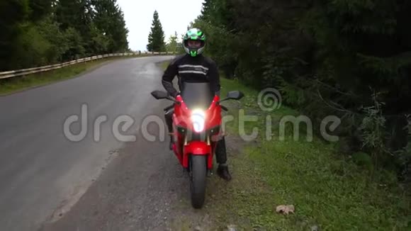一个骑摩托车的人年轻的帅哥骑摩托车在山路上他坐在摩托车上视频的预览图