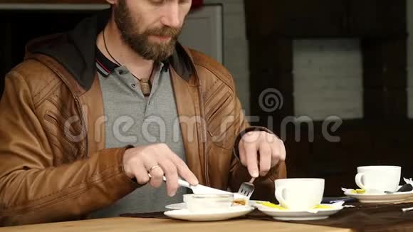 大胡子男人正在户外咖啡馆的露台上吃早餐慢动作视频的预览图