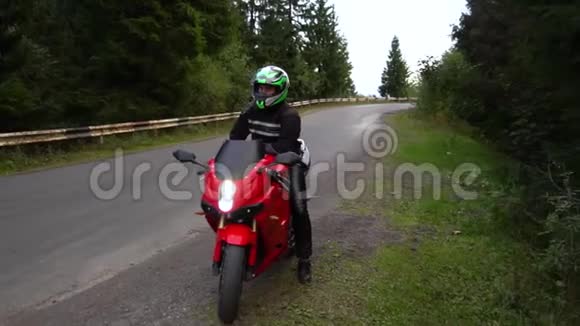 一个骑摩托车的人年轻的帅哥骑摩托车在山路上他坐在摩托车上视频的预览图