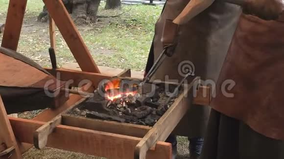 铁匠把钢坯放在粘土炉里的热煤上铁匠加热铁金属剑制造视频的预览图