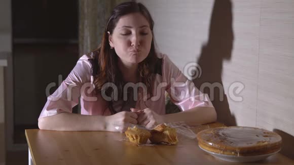 晚上在厨房吃面包的年轻女人视频的预览图