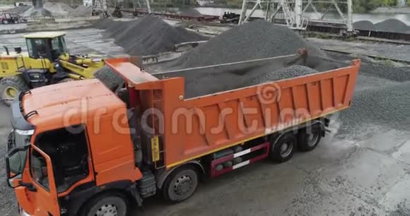 一辆挖掘机在卡车车身上装载碎石装载卡车的鸟瞰图视频的预览图
