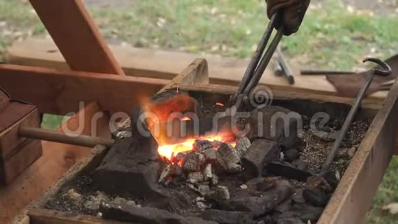 铁匠把钢坯放在粘土炉里的热煤上铁匠加热铁金属剑制造视频的预览图