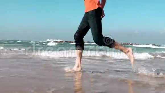 特写男腿沿着海滨夏日海滩奔跑自由概念低角度侧视享受假期的人4K视频的预览图