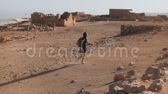 带背包的女孩探索沙漠废墟美丽的欧洲女性旅行者漫步在古老的风景中马萨达以色列4K视频的预览图