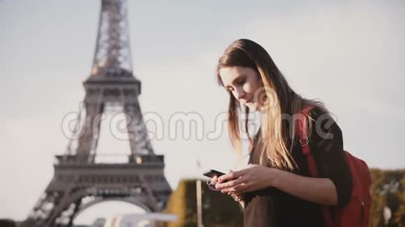 年轻漂亮的女人站在法国巴黎埃菲尔铁塔附近用智能手机和朋友聊天视频的预览图