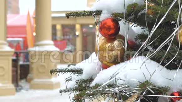 用球和玩具装饰的圣诞树她站在街上下雪了在背景中节日视频的预览图