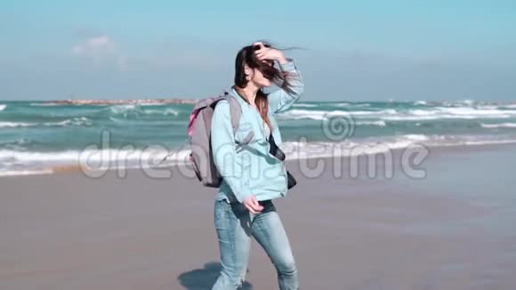 美丽的欧洲女人走在阳光明媚的海滨漂亮女孩微笑着看着镜头风吹拂着头发慢动作视频的预览图