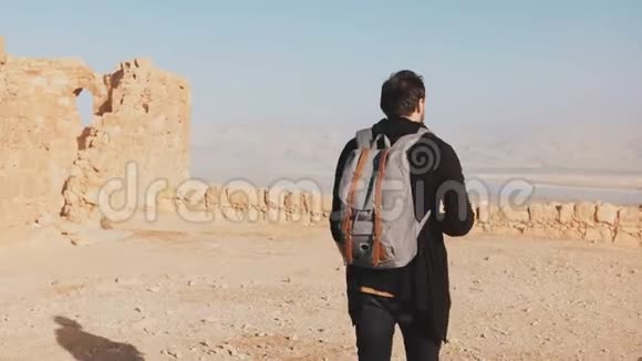 背着背包的人走在沙漠山顶上休闲记者博主拍摄死海风光以色列4K视频的预览图