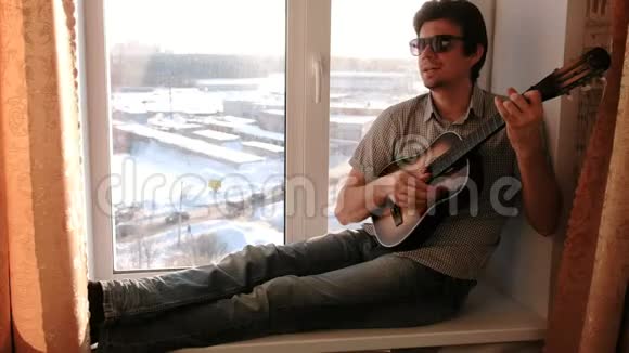 演奏乐器戴太阳镜的人在弹吉他坐在窗台上唱歌视频的预览图
