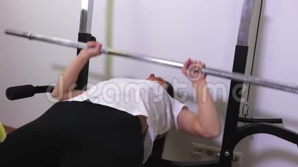 健身椅上的女人用杠铃做俯卧撑视频的预览图