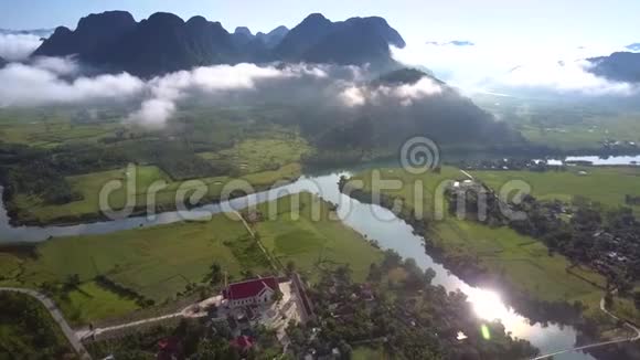 在乡村山谷上空飞行有房子树木和阳光反射着河流视频的预览图