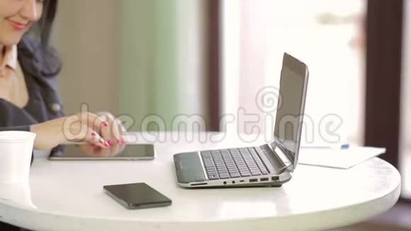 一个穿着深色夹克在平板电脑上工作的年轻女人的手视频的预览图