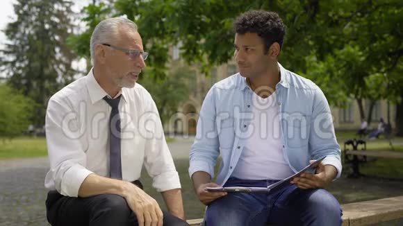 历史老师在大学附近和西班牙裔男子谈话讨论论文视频的预览图
