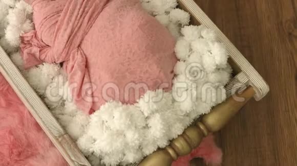 两周大的女婴头上有一个边缘裹着一条粉红色的毯子静静地睡在一个木制的摇篮里视频的预览图