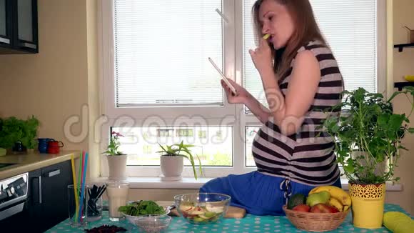 孕妇坐在厨房的桌子上吃水果视频的预览图
