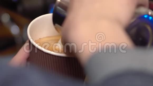 咖啡师女人在咖啡中加入牛奶并在牛奶泡沫拿铁上制作图案叶子视频的预览图
