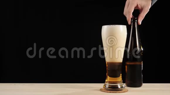 新鲜啤酒啤酒杯杯中的美味工艺啤酒放在黑色背景下的木桌上带水的冷鲜啤酒视频的预览图
