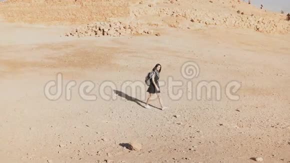 带背包的女人走向沙漠废墟年轻的高加索女性旅行者在干燥的沙子岩石墙壁上马萨达以色列4K视频的预览图