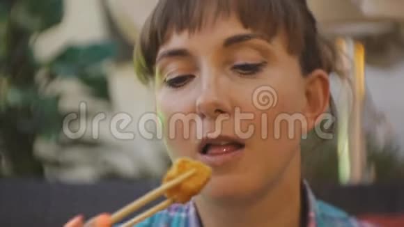 尝试日本料理的女人一位迷人的白种人年轻女子她咬着油炸豆腐带着它视频的预览图