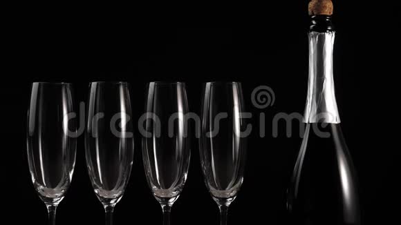 好香槟酒四个空玻璃杯香槟和一瓶香槟放在黑底木桌上视频的预览图