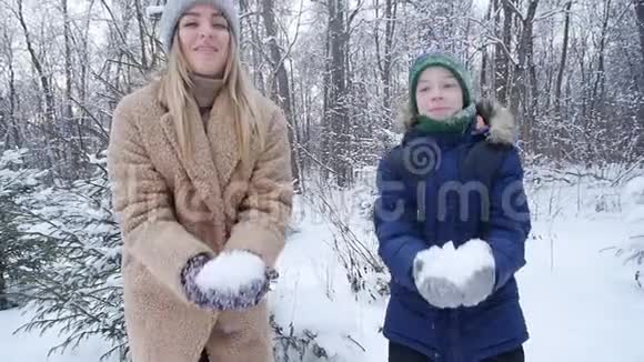 冬天的乐趣母亲和儿子在冬天的森林或公园里向空中撒雪快乐视频的预览图